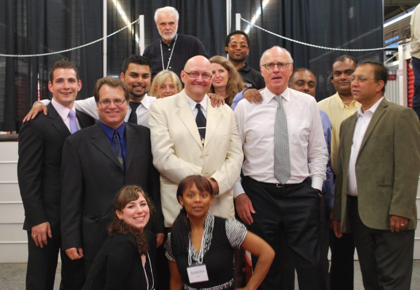 The All Canadian Self Storage Team, group of over 10 people standing, black curtain background