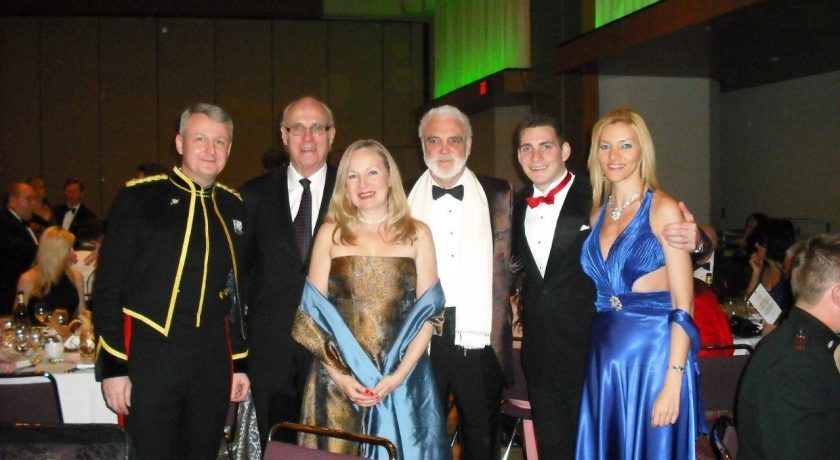 Garrison Ball, four men wearing suits and two women wearing gold and blue dresses