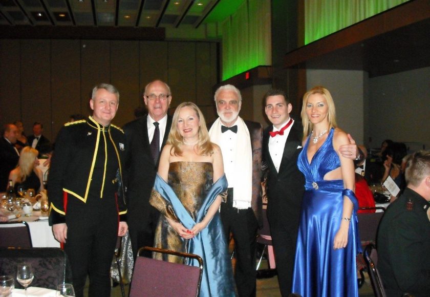 Garrison Ball, four men wearing suits and two women wearing gold and blue dresses