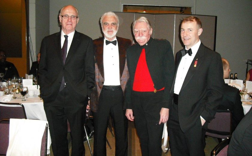 Garrison Officer's Ball, four men wearing suits, purple chairs and white tables in the background