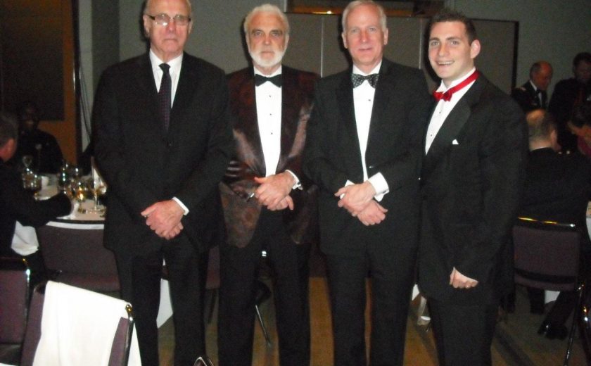 Garrison Officer's Ball, four men wearing suits, purple chairs and white tables in the background