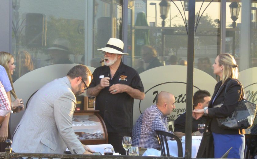 group of people sitting or standing on patio, glass windows behind them, black gate surrounding patio