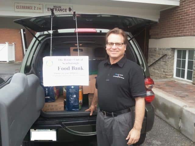 Man standing in front of open car trunk at the Rotary Club of Scarborough Food Bank event