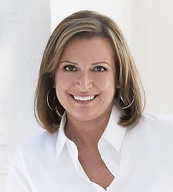 Woman with shoulder length hair wearing a white blouse shirt smiling