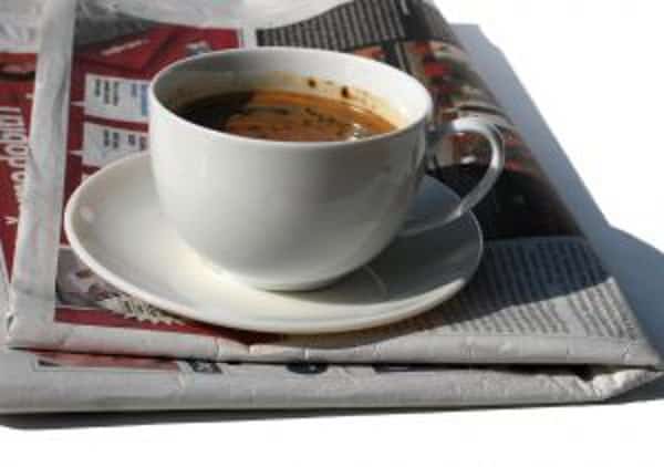 white coffee cup on a white plate on top of a newspaper