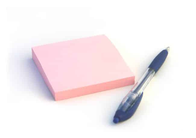 pink sticky note pad with a blue pen beside it