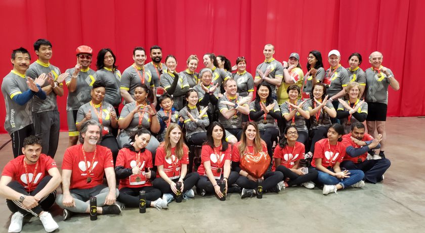 XYZ Storage team taking a group picture wearing yellow, grey, white, and red colours, in front of a red curtain