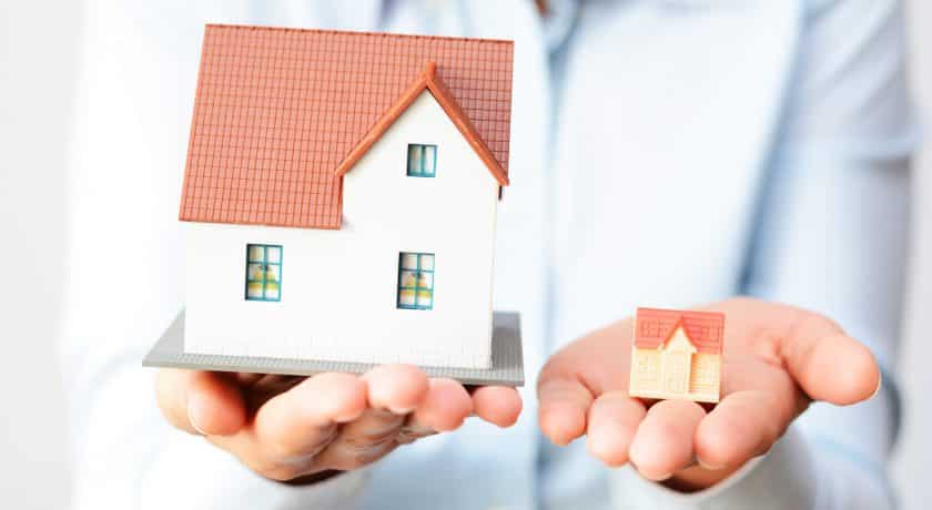 person holding big house in left hand and small house in right hand