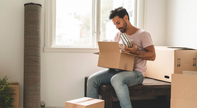 A mature hispanic man is packing and unpacking as he is moving into a new house.