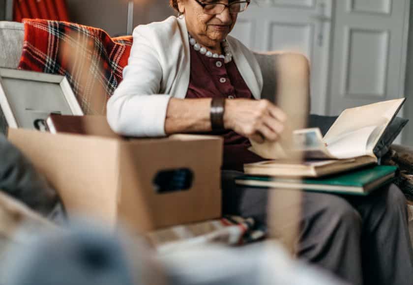 Old woman sitting in sofa and watching photos when she was young