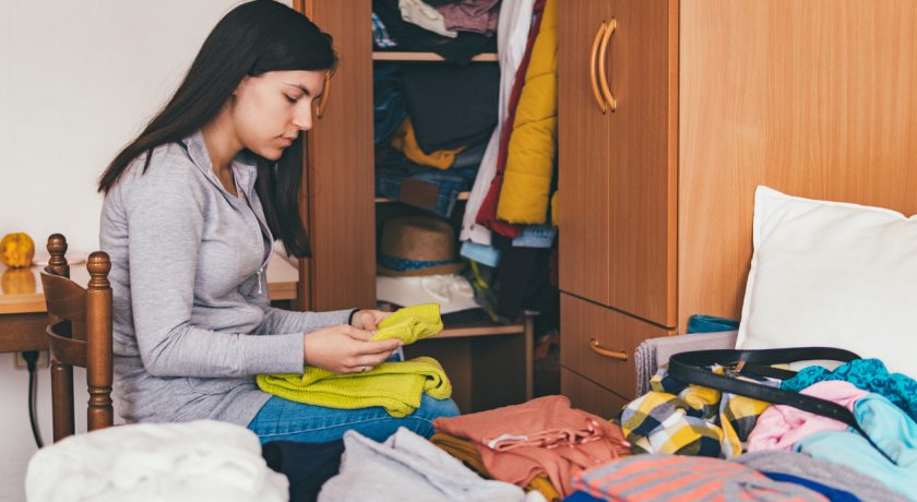 Young woman folding clothes and sorting it wardrobe.