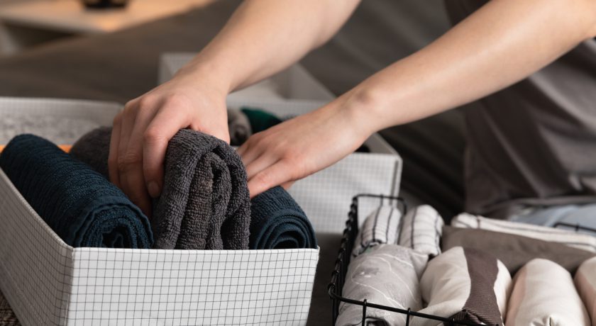 Vertical storage of clothing.Women organize clothes in a modern bedroom. Women sorting clothes in baskets room cleaning concept.